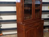 a wooden china cabinet with glass doors in a room