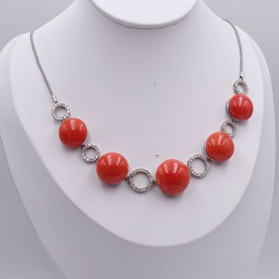collier composé de perles de corail et de diamants, porté par un mannequin blanc