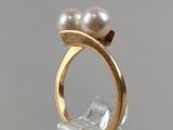 pearl and gold ring on a clear acrylic base