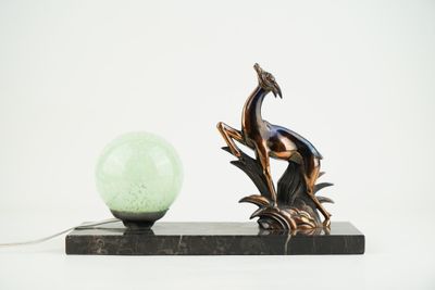 une statue représentant un oiseau perché sur une branche à côté d'une lampe