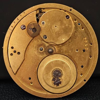 une image montrant un gros plan du cadran doré d'une horloge sur une surface noire