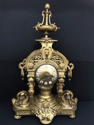 a gold clock that is sitting on a black surface