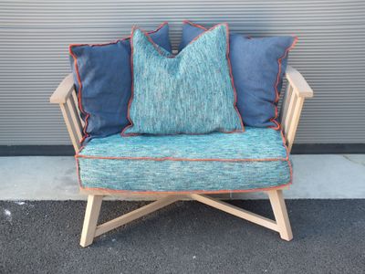 une chaise en bois avec des coussins bleus, posée devant un mur