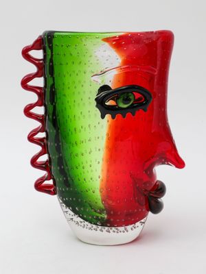 a red and green vase with a face on it