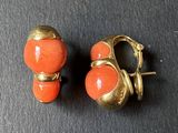 deux paires de boucles d'oreilles orange et dorées posées sur un fond noir