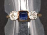 un gros plan d'une bague sertie d'une pierre bleue et de trois diamants