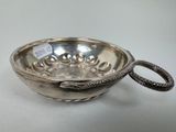 un bol ancien en argent, orné d'une poignée en forme de serpent, posé sur une table blanche