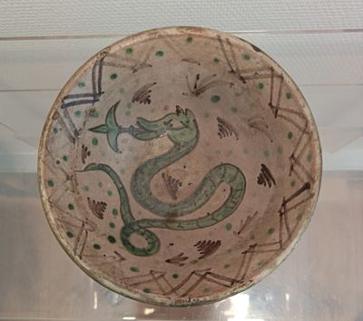 a bowl with a snake on it on display in a glass case