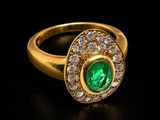 an emerald and diamond ring on a black surface