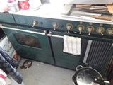a green stove top oven in a kitchen with pots and pans on it