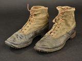 pair of old military boots on a black surface with a black background