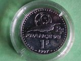 a silver coin in a clear plastic container on a green surface