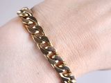 gold plated bracelet on a woman ' s wrist with a chain around it
