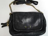 un sac à main en peau de serpent noir, muni d'une bandoulière à chaîne et d'un pompon