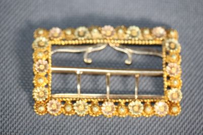 an image of a gold broochle with pearls on it