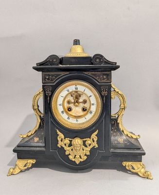 a black and gold clock sitting on a white surface