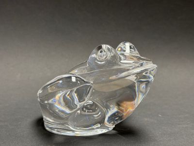 clear glass figurine of a frog on a black surface