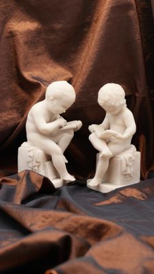 two figurines of children sitting on a bench