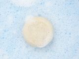 soap bubbles in a blue bathtub with a small round object