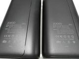 two black cell phones are sitting side by side on a white surface