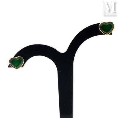 a close up of a pair of green earrings on a black stand