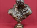 un buste antique en bronze représentant un jeune garçon, sur fond rouge