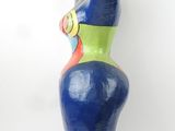 blue and green sculpture of a woman holding a tennis racquet on a black base