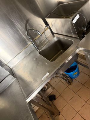 a small kitchen with stainless steel counter tops and a blue bucket