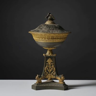 une urne richement décorée d'or et d'argent, surmontée d'un oiseau