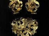 three gold brooches with leaves and flowers on a black background