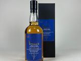 une bouteille de whisky dans un coffret, posée sur une surface blanche