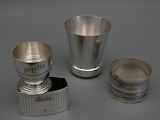 trois tasses en argent et un porte-tasse posés sur un plan de travail gris
