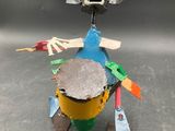 a metal sculpture of a bird holding a drum