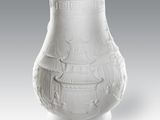 un vase blanc posé sur une table, sur fond gris