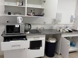 a kitchen with a sink, stove, microwave, and a trash can