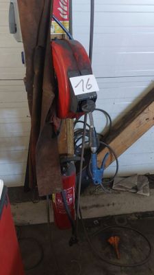 une borne d'incendie rouge posée dans un garage, à côté d'un tas de bois