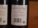 two bottles of wine sitting on a shelf next to each other