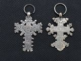 two silver crosses are shown on a black surface