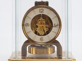 une horloge posée sur une table, dans une vitrine en verre
