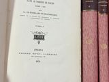 Plusieurs livres sont empilés sur une étagère dans une bibliothèque.