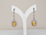 a pair of yellow and white earrings on a white stand