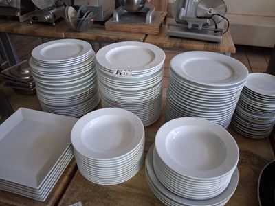 a lot of white plates on a table in the kitchen