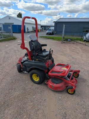 a red lawn mower sitting on top of a dirt field