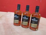 trois bouteilles de rhum posées sur une table devant un mur rouge