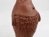 a brown vase with a bird on it next to a cookie