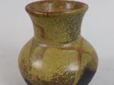 a brown and black vase sitting on a white surface