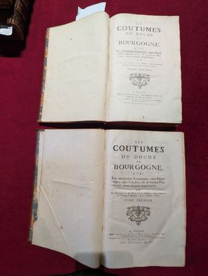 deux livres ouverts posés sur une table, à côté d'une bouteille de vin