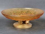 a glass bowl on a gold stand on a gray surface