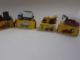 Quatre camions miniatures sont alignés les uns à côté des autres sur une surface blanche