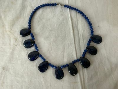 a necklace with blue beads and blue stones on a white cloth